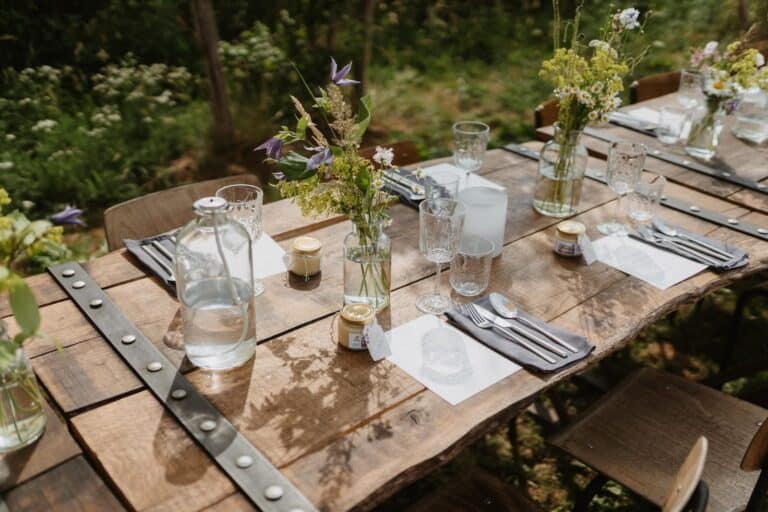 Gedeckte Holztafel mit Blumen, Gläsern und natürlicher Tischdekoration