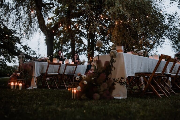 Abendliche Stimmung mit Lichterketten und langer Tafel bei einer Outdoor-Hochzeit an einem Airbnb-Ferienhaus.