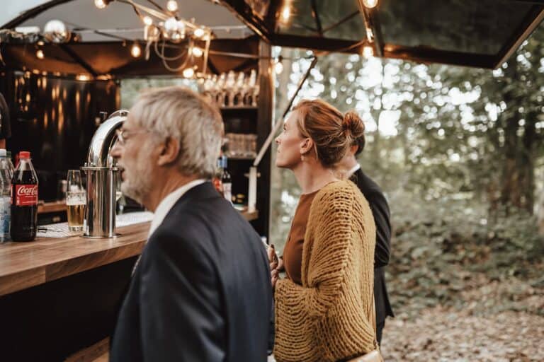 Gäste an einer mobilen Bar bzw. einem Foodtruck bei einem Outdoor Get-together auf privatem Grundstück während einer Hochzeit im Grünen
