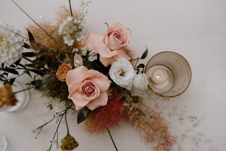 Detailaufnahme der inhouse umgesetzten Tischdekoration mit Wildflower Floristik, Verleihdekoration aus dem Hey Happy day Fundus und Kerzen bei einer Outdoor-Hochzeit an einem privaten Ferienhaus.