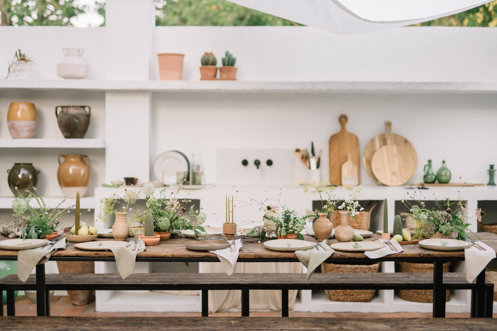 Stilvoll gedeckte Tafel mit Blumen, Kerzen und Naturmaterialien für eine private Gartenparty geplant von Hey Happy Day Hochzeitsplanung und private Events mit offener Outdoor-Küche.