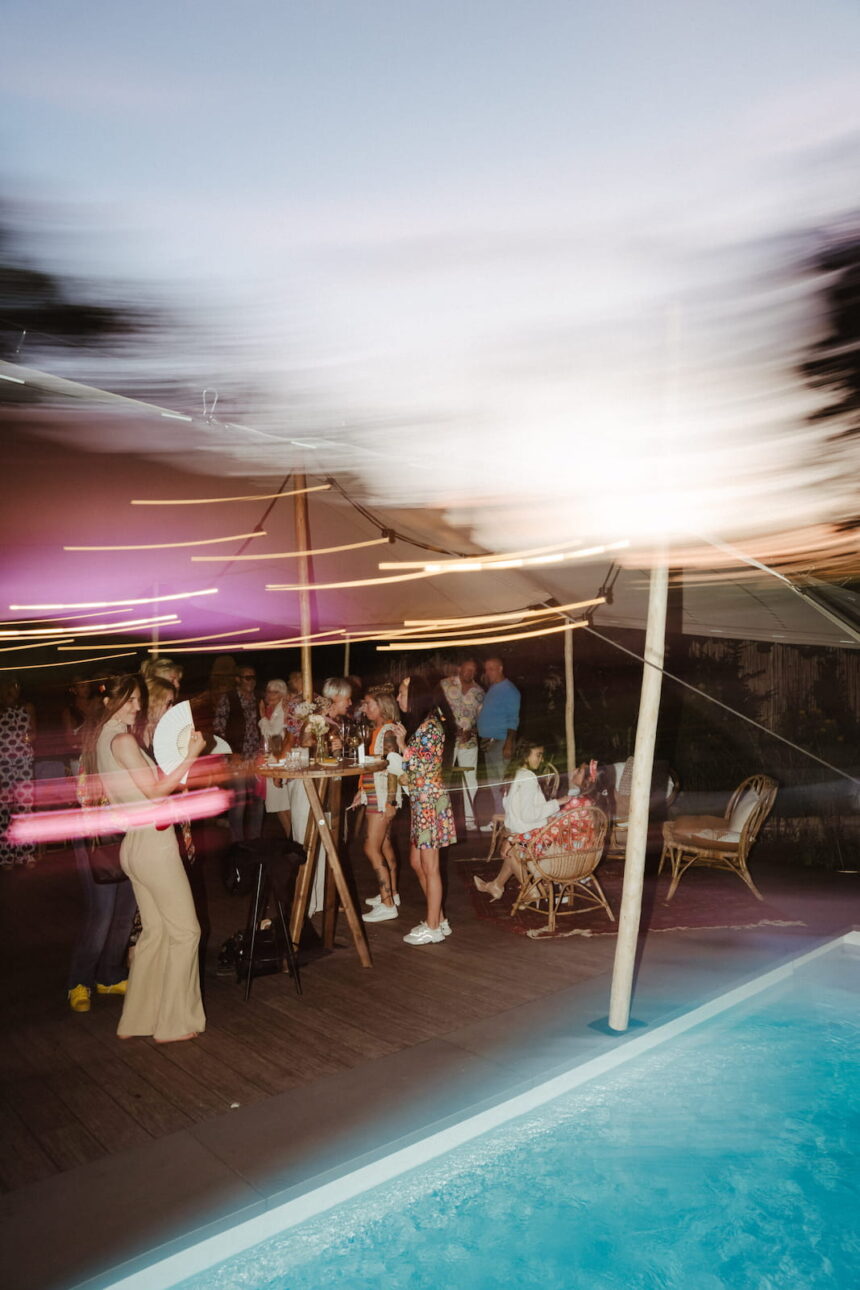 Schwarz-Weiß-Aufnahme einer ausgelassenen privaten Feier mit Gästen und Musik unter einem beleuchteten Festzelt geplant von Hey Happy Day Partyplanung und private Eventplanung. 