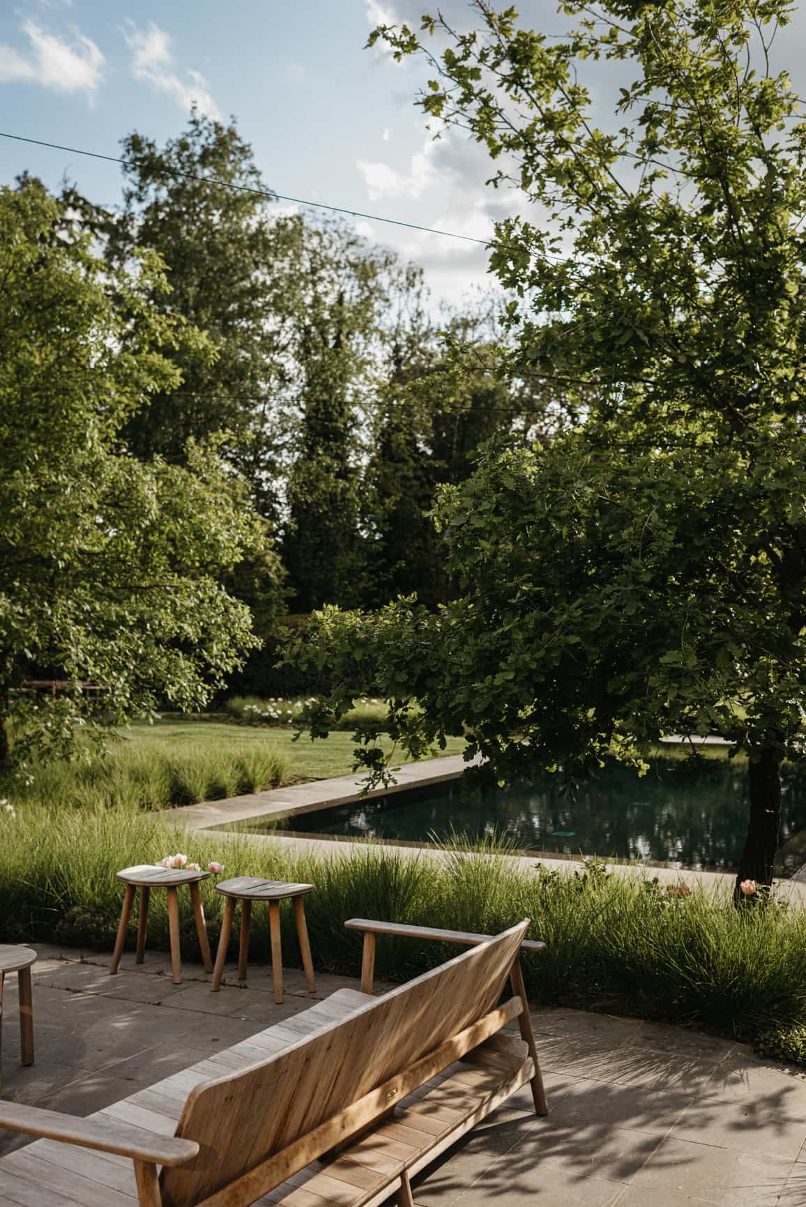 Naturnaher Garten mit Pool, Holzbank und gemütlichen Sitzplätzen – ein privates Anwesen als außergewöhnlicher Ort für eine Hochzeit zu Hause.