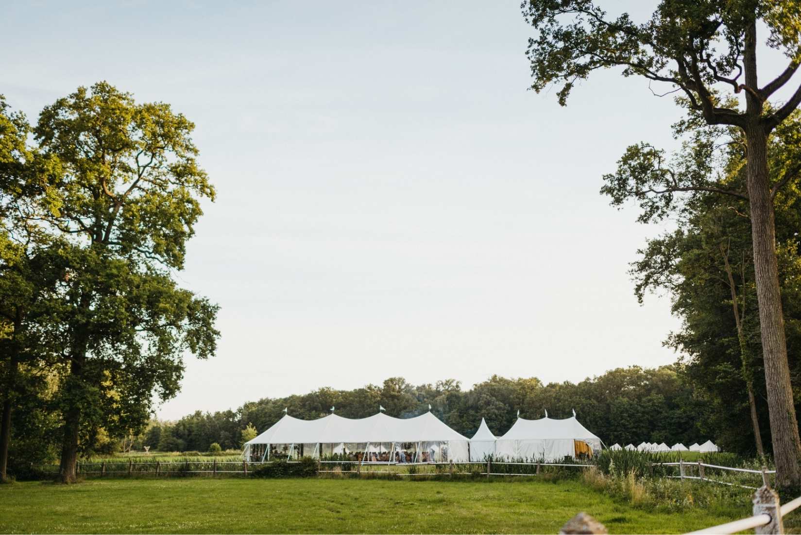 Großzügige Hochzeitszelte auf einer grünen Wiese zwischen alten Bäumen – Outdoor-Gartenhochzeit im Stil einer exklusiven Private Estate Wedding.