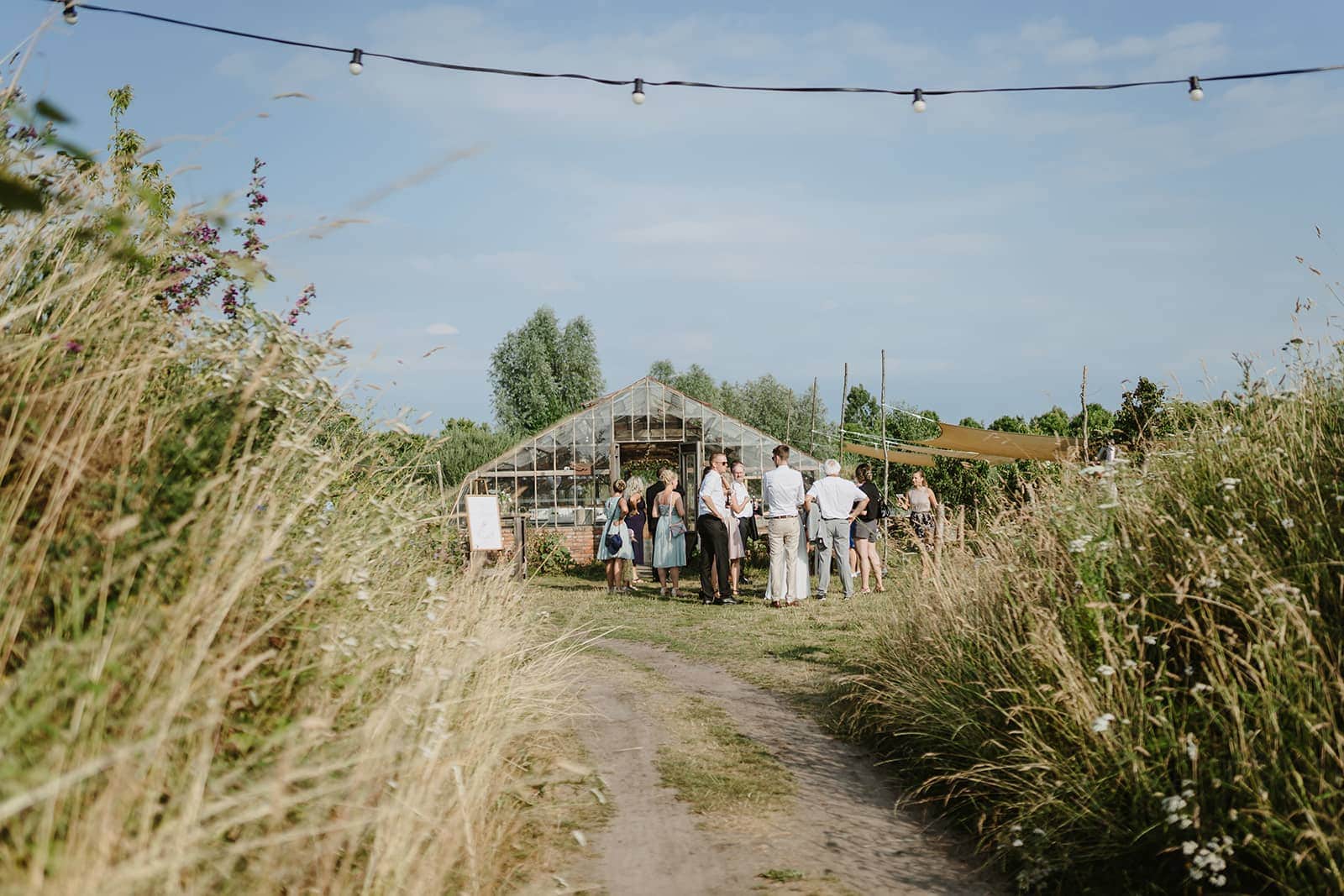 Gäste auf dem Weg zu einer Outdoor-Hochzeit mit Gewächshaus als Plan B inmitten der wilde Natur – Hochzeit planen lassen von  Hochzeitsplaner Hey Happy Day aus NRW, Düsseldorf, Köln, Ruhrgebiet tätig deutschlandweit, in Holland, Belgien, Mallorca und Europa.