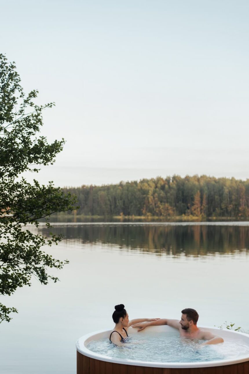 Paar entspannt gemeinsam im Whirlpool direkt am See – besondere Momente während eines Wedding Weekends in der Natur.
